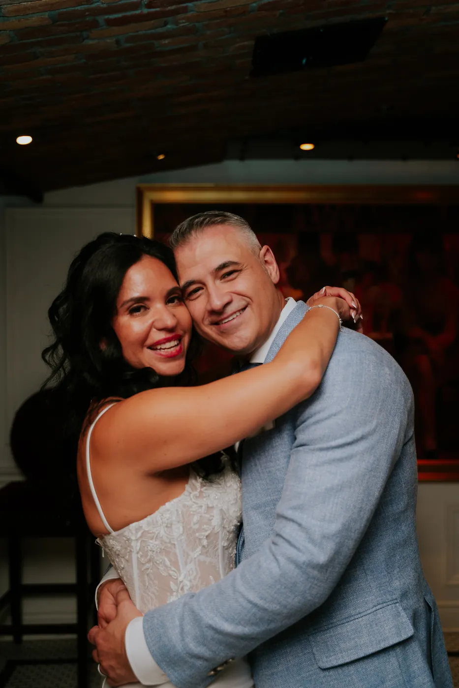 The bride embracing a man in a light blue suit at the reception.
